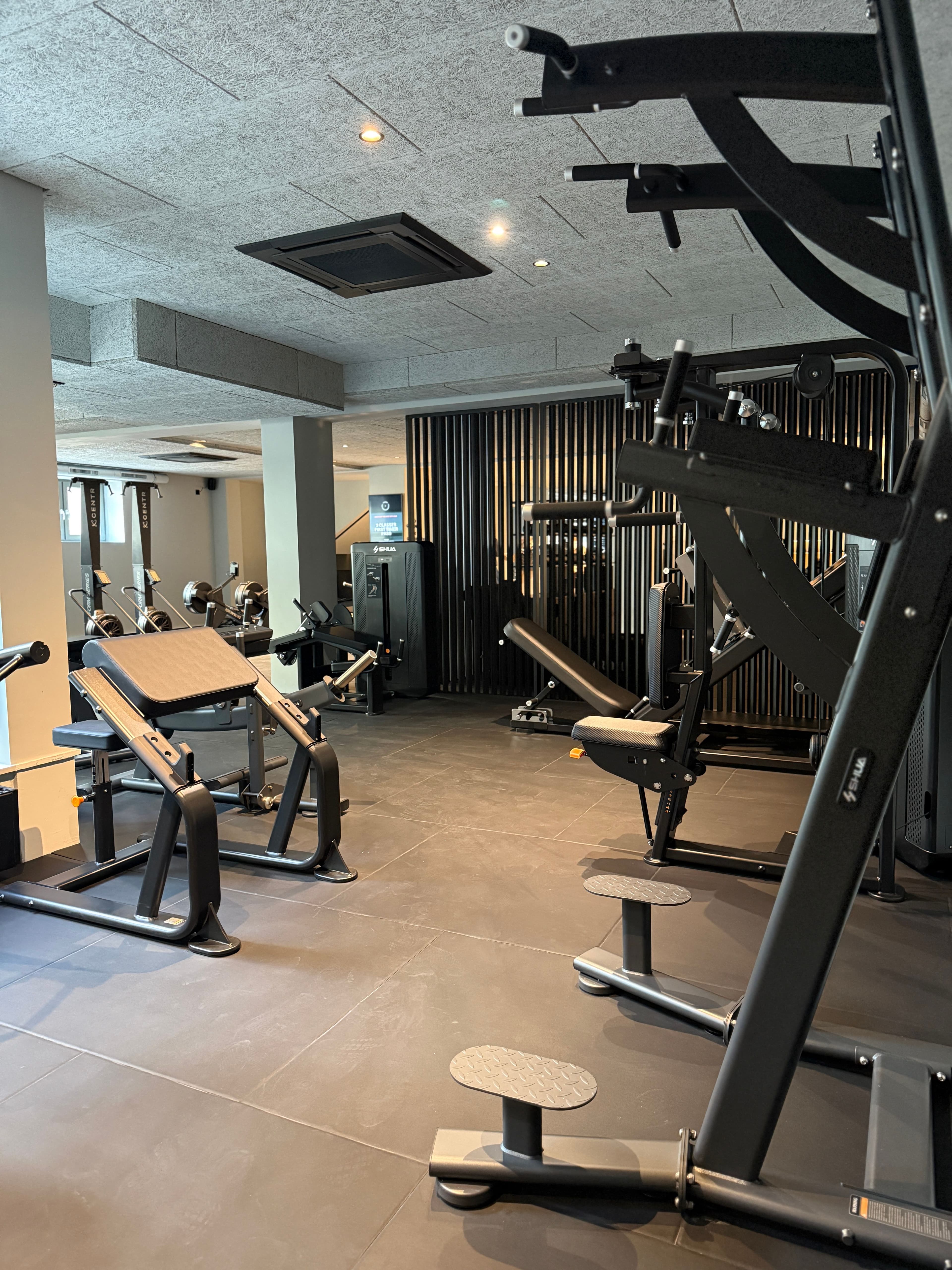 A view across the strength training area with machines and workout benches at THE BACE.