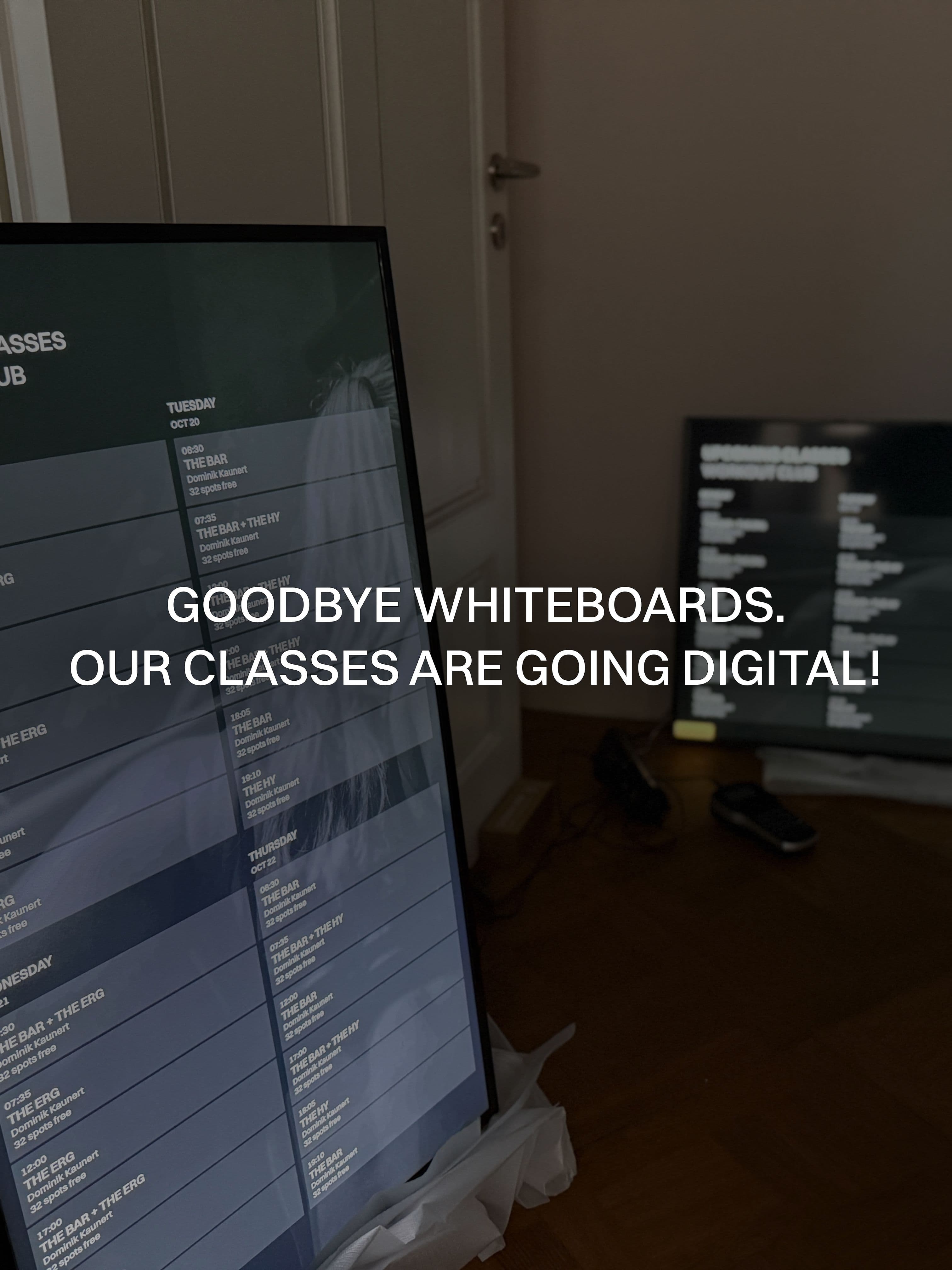 Digital screens displaying class schedules and workout information, replacing whiteboards.